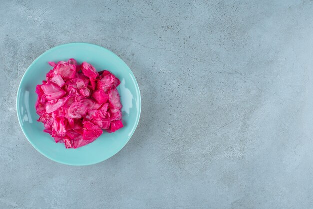 Crauti fermentati rossi sul piatto, sulla tavola blu.