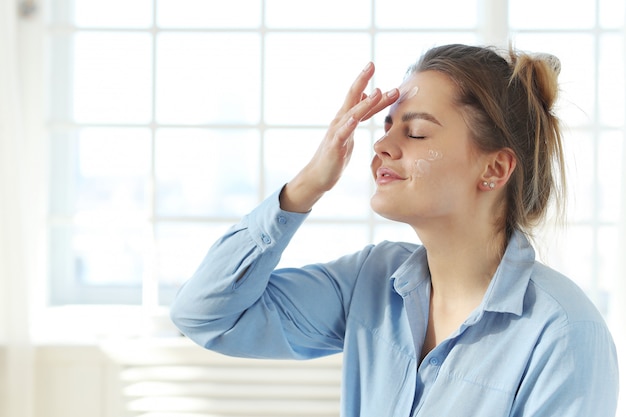 Crema facciale di diffusione della giovane donna. Concetto di cura della pelle.