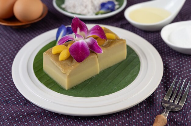 Crema pasticcera su una foglia di banana in un piatto bianco con fiori di pisello e orchidee