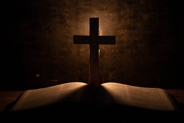 Croce con la Bibbia e la candela su un vecchio tavolo di legno di quercia.