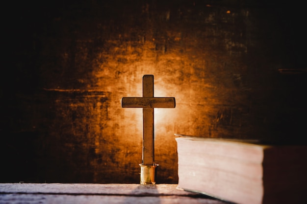 Croce con la Bibbia e la candela su un vecchio tavolo di legno di quercia.
