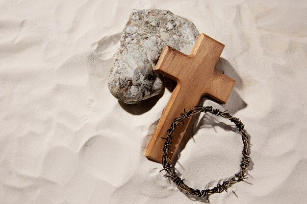 Croce di legno ad alto angolo e corona di spine sulla sabbia