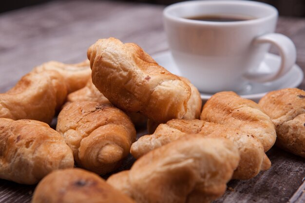 Croissant appena sfornati su tavola in legno rustico con tazza di caffè. Caffè delizioso.