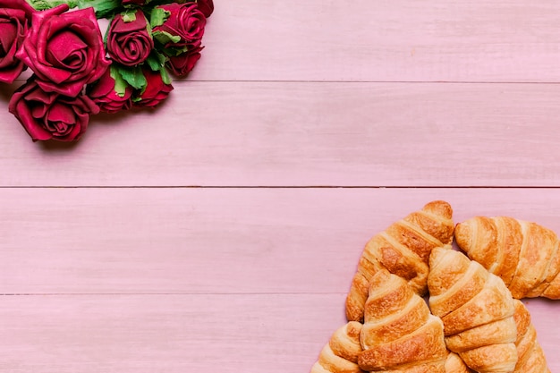 Croissant con bouquet di rose rosse sul tavolo