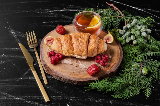 Croissant con frutti di bosco sul piatto di legno.