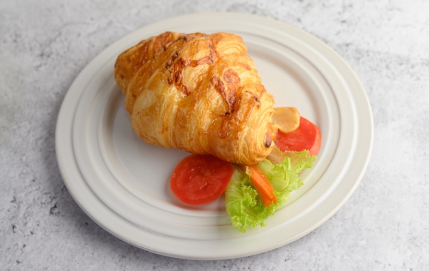 Croissant con hot dog sul piatto bianco