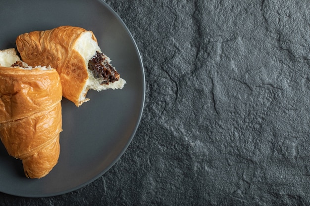 Croissant con ripieno di cioccolato su fondo scuro.