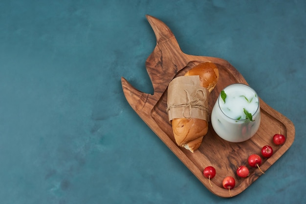 Croissant con una tazza di latte e ciliegie.