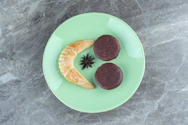 Croissant fatti in casa e biscotti al cioccolato sul piatto verde.