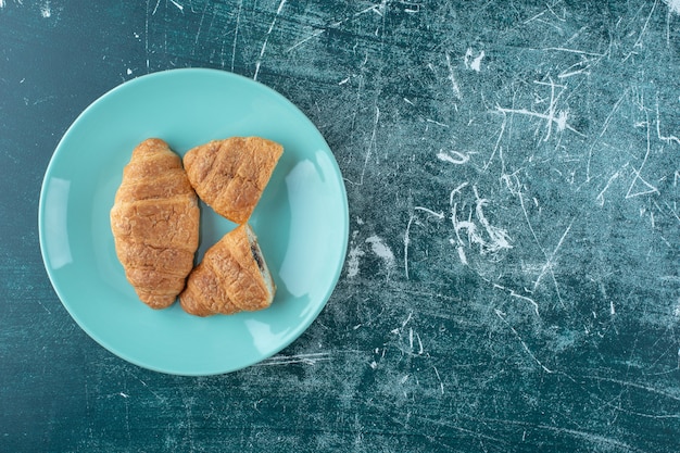 Croissant fatti in casa su un piatto, sullo sfondo blu. Foto di alta qualità