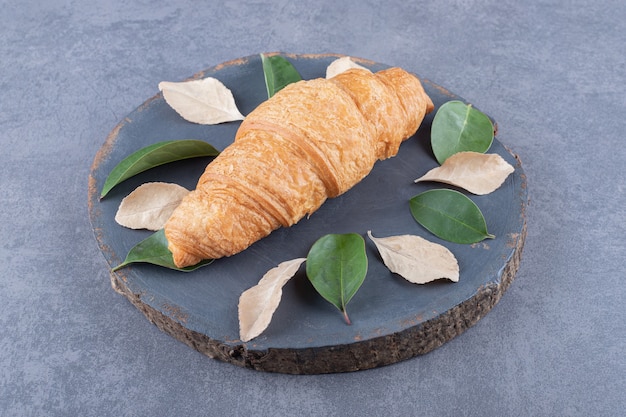 Croissant francese appena sfornato sul bordo di legno grigio su sfondo grigio.