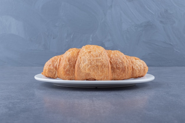 Croissant francese fresco sulla zolla bianca.