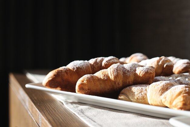 Croissant freschi con croissant con zucchero a velo su un tavolo di legno