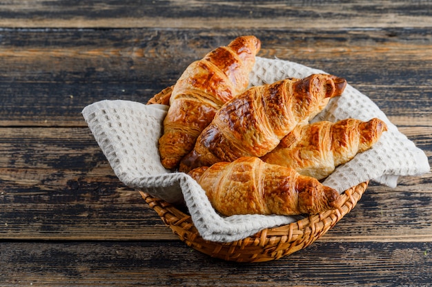 Croissant in un cestino sulla tavola di legno, vista dell'angolo alto.