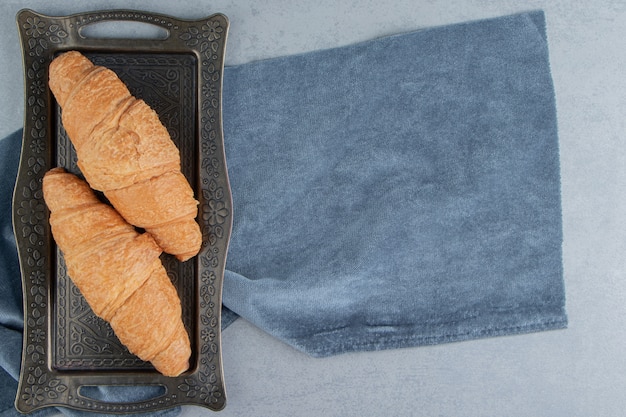 Croissant in vassoi su asciugamano, sullo sfondo di marmo. Foto di alta qualità