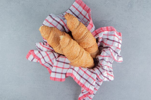 Croissant nella ciotola su asciugamano, sullo sfondo di marmo. Foto di alta qualità