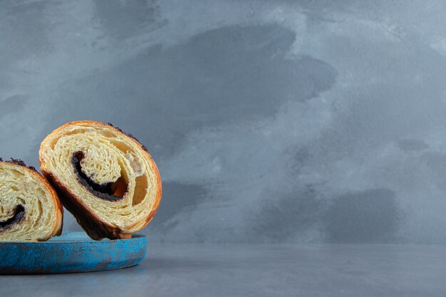 Croissant tagliati a metà con cioccolato su piatto blu.