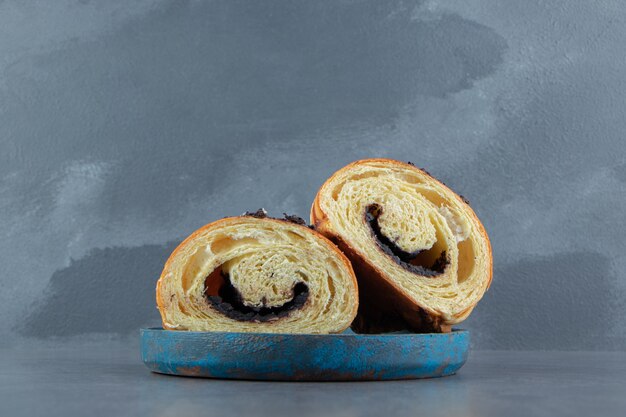 Croissant tagliati a metà con cioccolato su piatto blu.