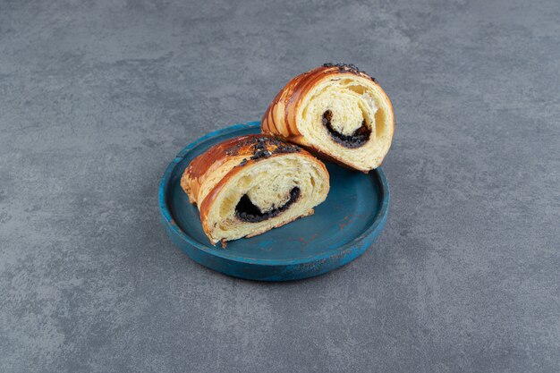 Croissant tagliati a metà con cioccolato su piatto blu.