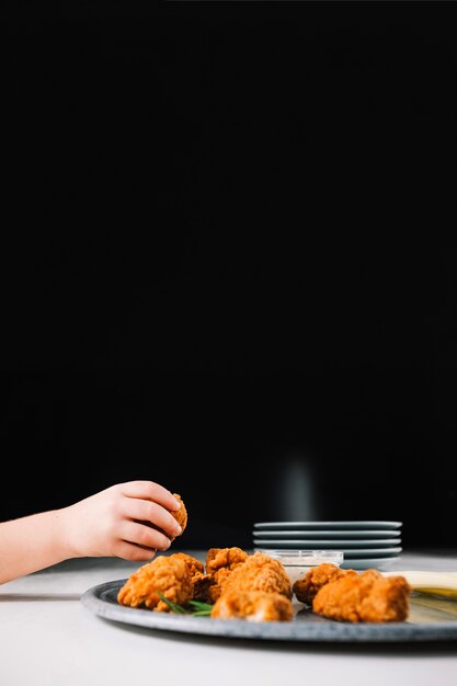 Crophand prendendo un pezzo di pollo fritto