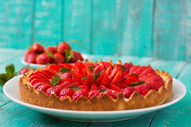 Crostata con fragole e panna montata decorata con foglie di menta.