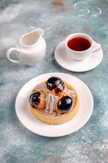 Crostata con profiteroles sopra con panna montata.