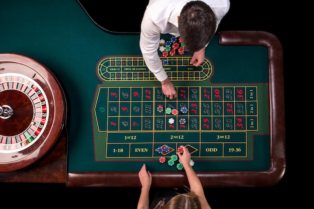 Croupier uomo e donna che giocano alla roulette al tavolo del casinò. Vista dall'alto a un tavolo da roulette verde con un metro a nastro.