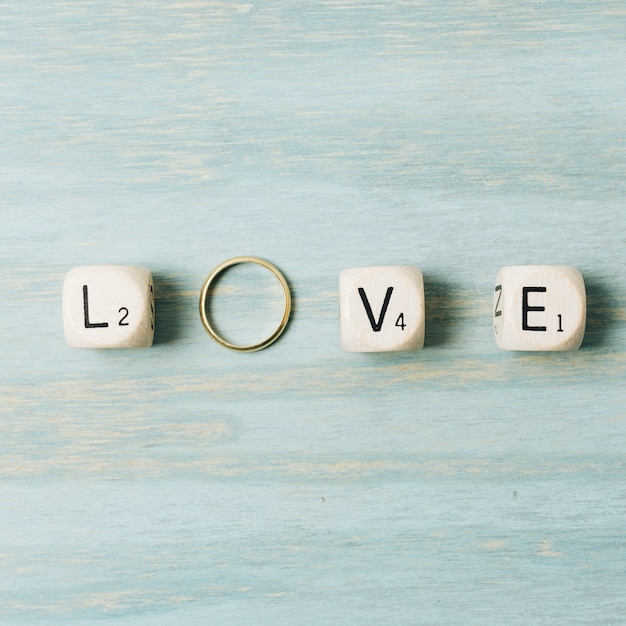Cubi della lettera di amore con l&#39;anello dorato di nozze sul contesto di legno di struttura