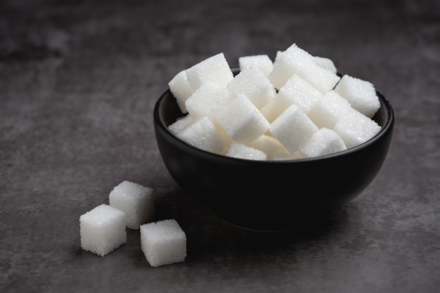 Cubi dello zucchero bianco in ciotola sulla tavola.