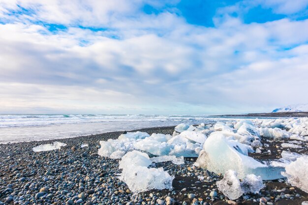 Cubo di ghiaccio che rompe sulla spiaggia rocciosa nera, paesaggio di stagione invernale dell&#39;Islanda