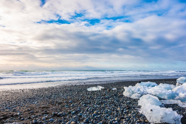 Cubo di ghiaccio che rompe sulla spiaggia rocciosa nera, paesaggio di stagione invernale dell&#39;Islanda