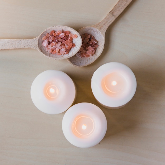 Cucchiai con sale aromatico vicino a candele