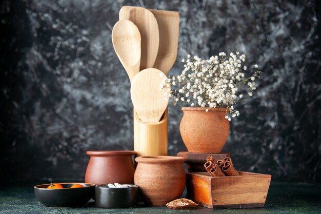 Cucchiai di legno di vista frontale con pentole e cannella sulla foto di posate di cibo sale condimento colore muro scuro