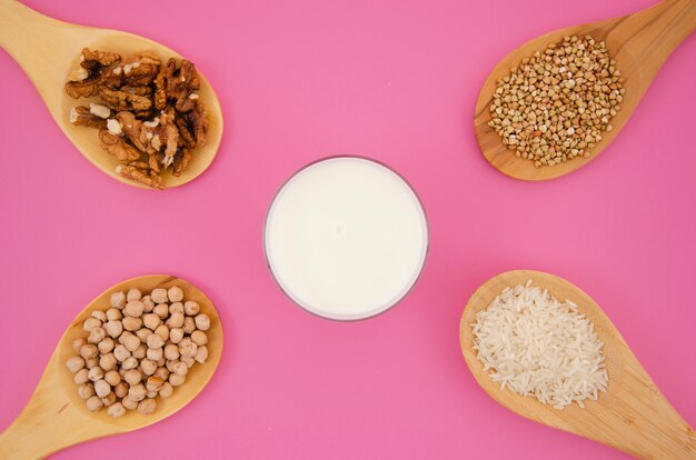 Cucchiaio con cereali e noci su sfondo rosa