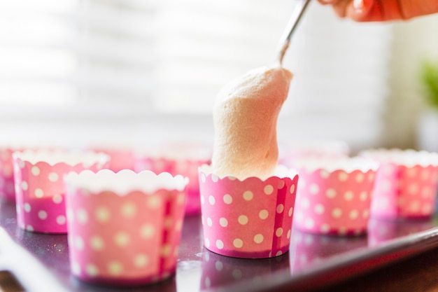 Cucchiaio di close-up e tazze rosa con pastella