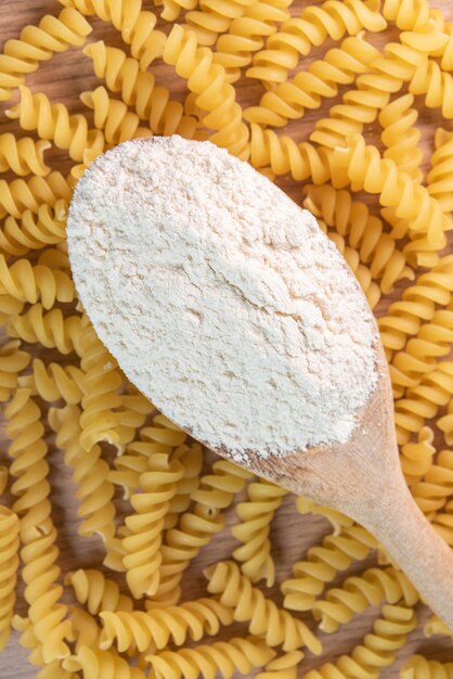 Cucchiaio di legno con farina di frumento su pasta cruda