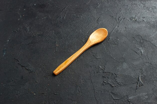 Cucchiaio di legno vista dal basso sullo spazio libero del tavolo scuro dark