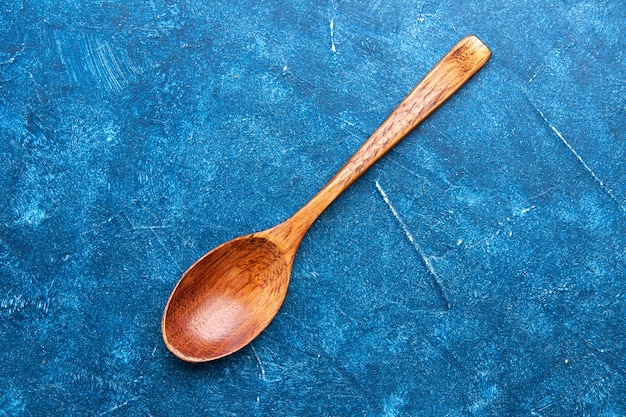 Cucchiaio di legno vista dall'alto sul tavolo blu con posto di copia