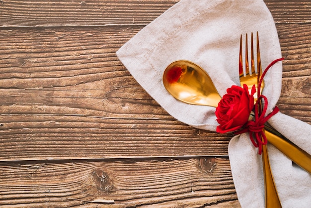 Cucchiaio e forchetta con fiore rosso sul tovagliolo