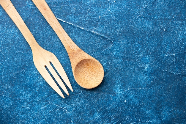 Cucchiaio forchetta di legno vista dall'alto sul posto libero tavolo blu