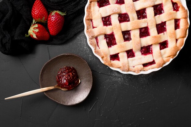 Cucchiaio riempito con marmellata di fragole e torta piatta disteso