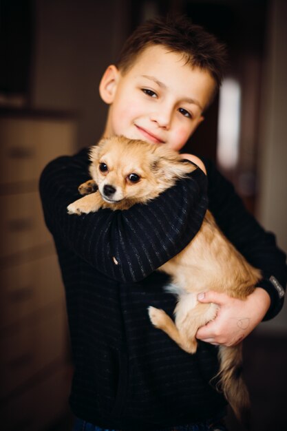 Cucciolo lanuginoso sulle braccia del ragazzo