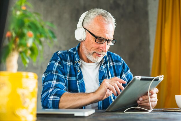 Cuffia da portare dell&#39;uomo maggiore facendo uso della compressa digitale