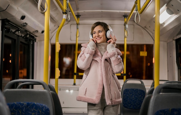 Cuffie d'uso della metà di colpo della donna in bus