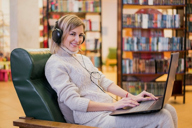 Cuffie da portare della donna che osservano a partire dal computer portatile