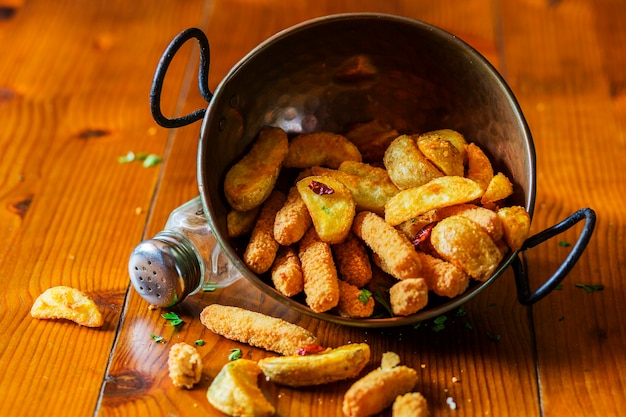 Cunei della patata fritta nell&#39;attrezzo di rame sulla tavola di legno