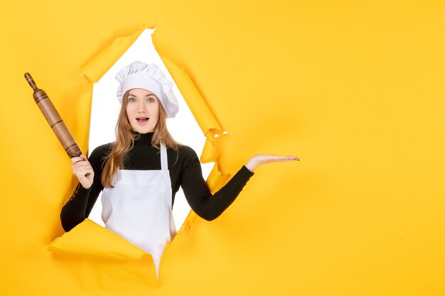 Cuoca di vista frontale che tiene mattarello sul sole giallo cibo cucina lavoro cucina foto