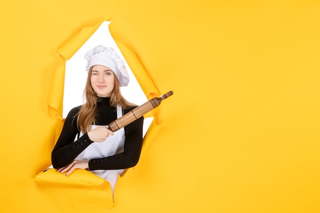 Cuoca di vista frontale che tiene mattarello sulla foto del sole del cibo del lavoro della cucina di colore giallo