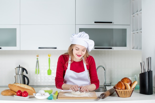 Cuoca sorridente di vista frontale che impasta il tagliere della pasta in cucina