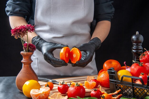 Cuoca vista frontale che taglia mandarini su insalata di cottura scura dieta salute pasto vegetale cibo frutta lavoro